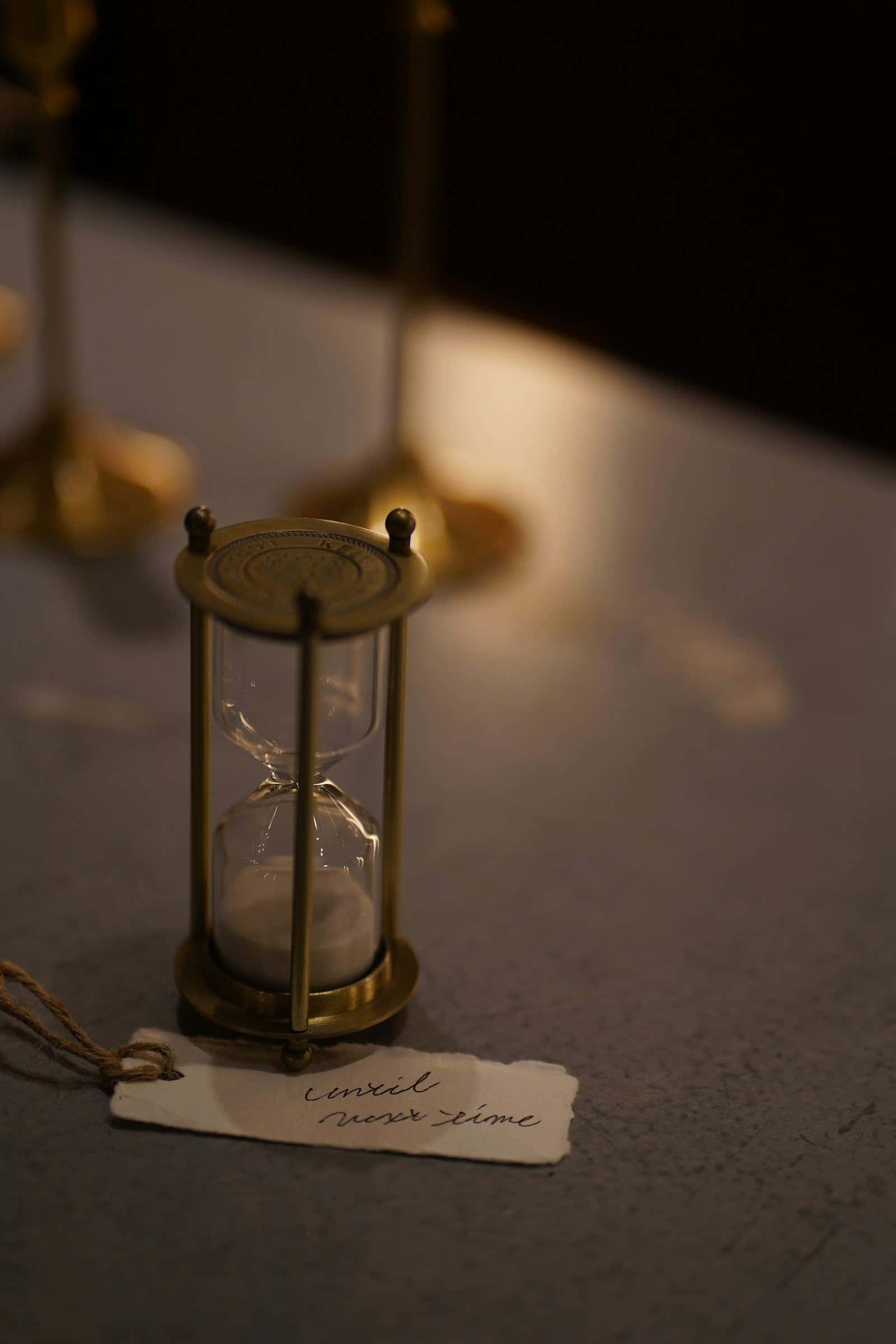 A brass hourglass on a table in low light