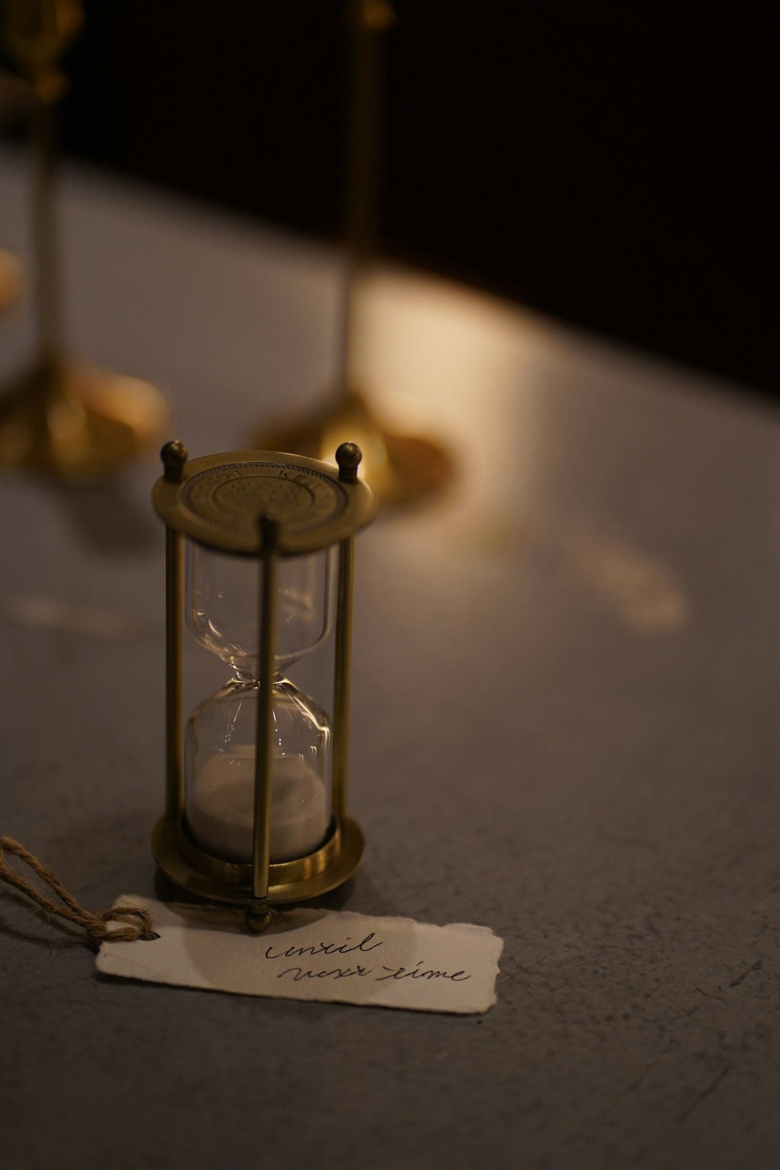 A brass hourglass on a table in low light